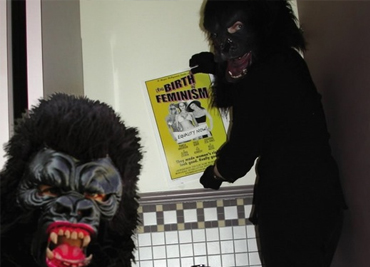 Guerrilla Girls Frida Kahlo and Kathe Kollwitz sticker a movie theater bathroom in Hollywood in 2003.